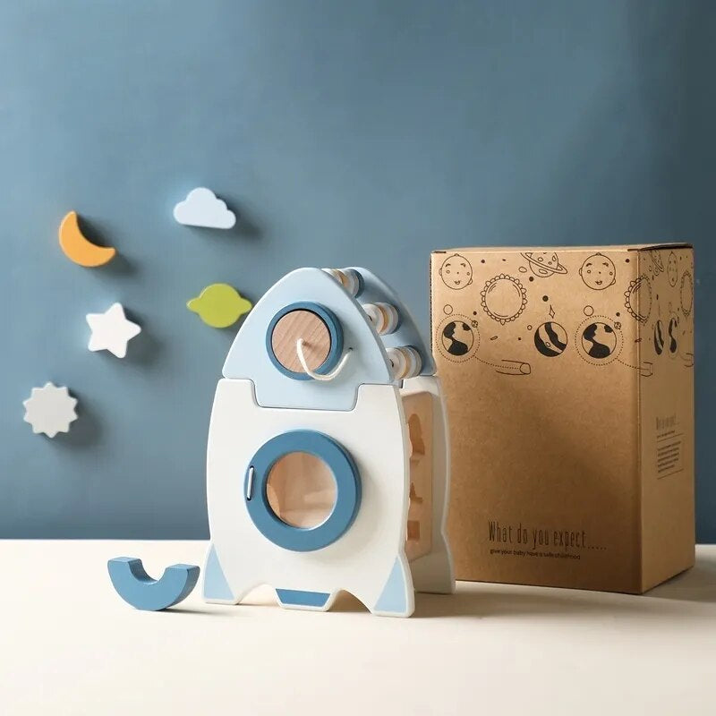 Wooden toy rocket with a cardboard box on a blue background